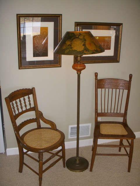 Antique side chairs with older lamp.  Signed artwork on wall