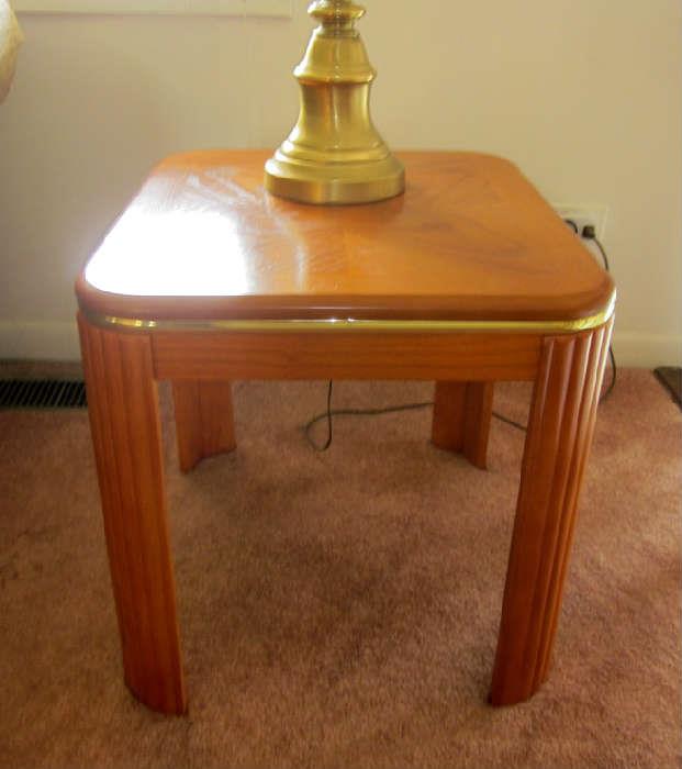Two wood end tables with goldtone trim and rounded corners.