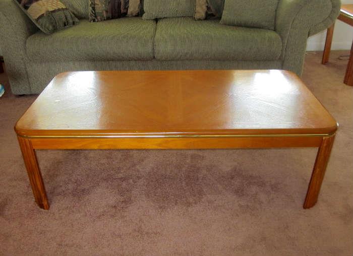 Wood coffee table with goldtone trim and rounded corners.