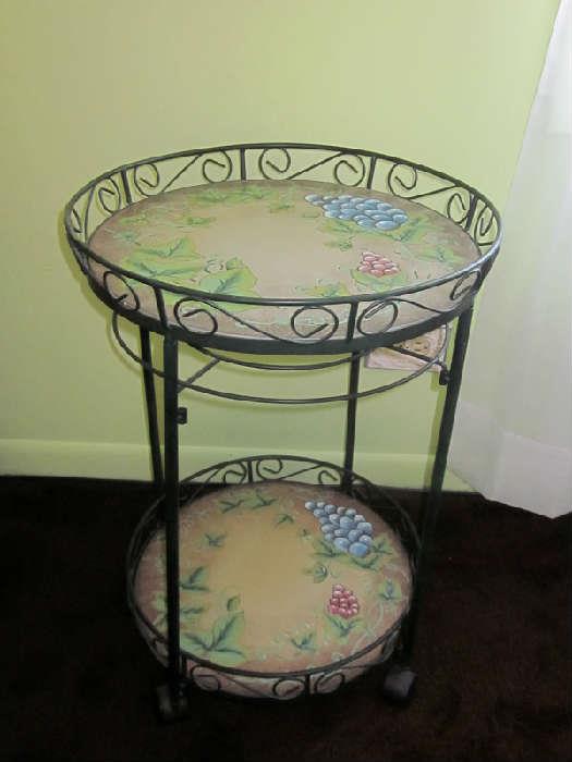 Two-tier wrought iron table on wheels.
