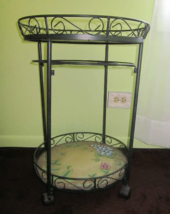 Two-tier wrought iron table on wheels.