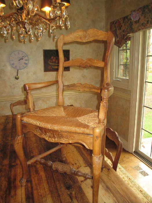  Vintage Country French Solid Ladderback Arm Chair. Intricate carvings grace the back, Natural Rush Seat.  Originally purchased at Old Plank Road Antiques.