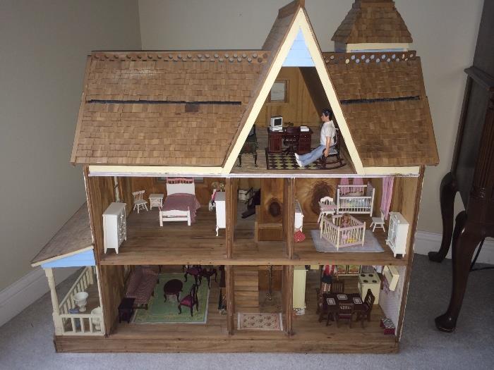 Large wooden dollhouse full of furniture and accessories.