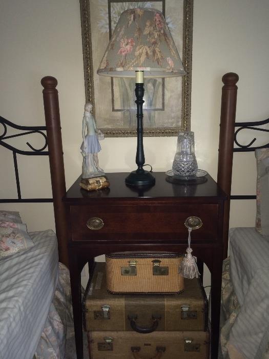Pair of twin beds, shown with small table, vintage suitcases and décor.