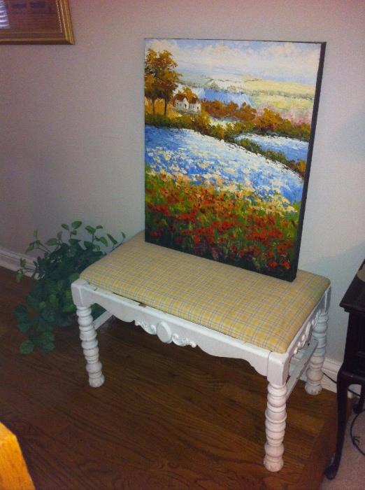 Painted bench with upholstered top and unframed painting.