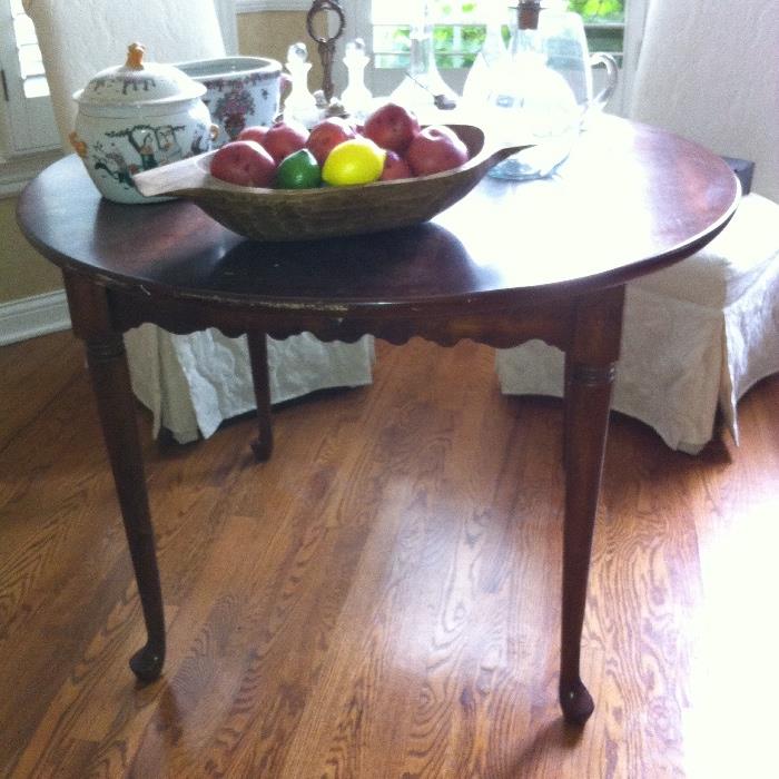 Walnut round table, two upholstered chairs, tabletop décor.