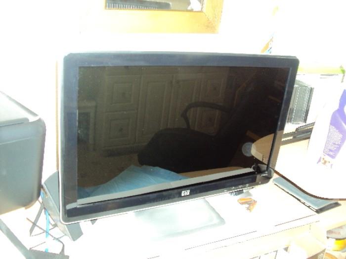 two computers with moniters and one smaller flat screen television 