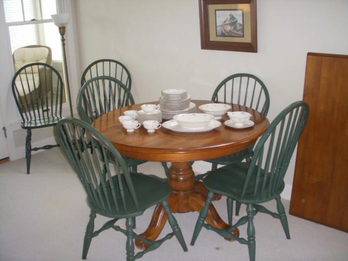 Round wood table with one leaf and 6 green chairs.
