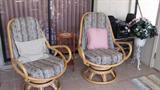Matching Rattan Swivel Chairs with Cushion backs and Seats; Also pictured is a Three Legged Three Tier Plant Stand and a Wrought Iron Plant Stand with a silk floral arrangement