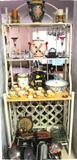 Wrought Iron Bakers Rack with open shelves storage and a wine rack too. Pottery, cup and saucer sets, glassware, bakewares and other items displayed are also for sale.
