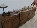 Vintage Colonial Style Set of Three Matching Cabinets with Storage and brass pulls...one has double door and drawers storage and the other two have drawers storage; Also shown is an accent table lamp with a glass half dome shade; Also shown are some of the depression and colored glasswares that are available and some of the collection of dolls which are also available.