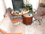 Dinette Set... sextagonal shaped table with pedestal style base,  oak wood ringed top with a  laminate insert, 4 matching chairs on caster mounts with neutral tan upholstered seats and backs.  Vintage Commode Style End Table with marble inset top and storage.   Also shown are some of the excellent glasswares available in this sale...as shown are some of the colored glasswares, and stemwares.  The Mitsubishi color TV shown is also available.