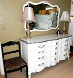 Vintage Continental Style Triple Dresser with 12 drawers storage with brass pulls and white Shabby Chic finish. Matching Continental Stylewall mirror with  beveled mirror .   Dresser and mirror are part of a Queen Size Bedroom Set with Shabby Chic White finish...this Set, in addition to the triple dresser and mirror,  includes Queen Size Headboard with White Shabby Chic finish, Queen Size Plush Serta Mattress & Boxsprings & Frame, Pair of Matching Night Stands with drawer and bookshelf storage and brass pulls and white Shabby Chic finish. ( other items  are shown elsewhere in this collection)  Also shown in the picture is a vintage press back chair with a carved rose accent and dark finish.  Also shown in the picture are a pair of  matching accent table lamps.