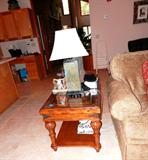 One of Two Matching End Tables with beautiful worm wood and rich finish,  carved fan accented top and with glass over top too, braded trim, bottom bookshelf storage, and nicely carved fluted legs. The other matching End Table is shown elsewhere in this collection. End Tables, Coffee Table are also matching to Armoire which is pictured elsewhere in this collection. Accent Table Lamp is one of two matching and is also available.