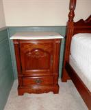 One of Two Matching End Tables by Stanley Furniture with marble tops, door and drawer storage with brass pulls,  and pressed decor accents.   End Tables are part of Stanley Furniture Bedroom Set that includes  Four Poster Style King Size Bed Set...King Size Four Poster Style Headboard & Footboard, frame, King Size Mattress & Boxsprings and matching End Tables.  The other matching end table is pictured elsewhere in this collection.