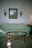 Contemporary Living Room Set - Elegant Sofa with Sea Foam Green upholstery, Oval shaped rattan & glass coffee table. Not shown in this picture are three occasional chairs and a large round end table that are pictured separately. Also pictured Accent artwork with countryside theme, matching shelf sconces with Norwegian / Scandanavian style carved figures