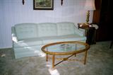 Contemporary Living Room Set - Elegant Sofa with Sea Foam Green upholstery, Oval shaped rattan & glass coffee table, Large Round Shaped Wood End Table, Accent Table Lamp.Not shown in this picture are three occasional chairs which are shown in separate pictures