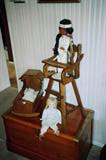 Vintage Doll Highchair with Native American Doll - "Pocahontus"; Medium Sized Wooden Chest / Trunk with Brass Hardware Accents. Note: Doll Cradle with BiLo Baby Doll and unmarked ceramic and cloth doll also pictured are not available.