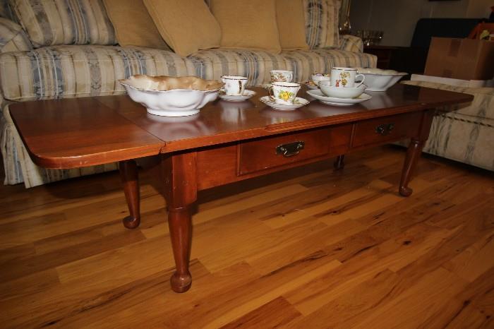 Long narrow coffee table with two drop leaf ends and double drawers. Tea cups and hand painted porcelain.