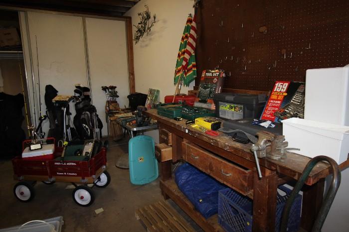 Radio Flyer wagon, three sets of golf clubs, golf bag wheels, large work bench, tool kits, patio umbrella and stand. 