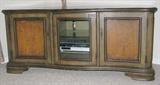 Pre-selling - This is a very nice television console, painted in pretty shades of olive green and gold with scrolled accents. The cabinet has 3 doors (two solid and one glass) and measures 64” wide x 24” deep x 28.25” tall. $350