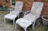 A pair of outdoor chairs with ottomans and cushions