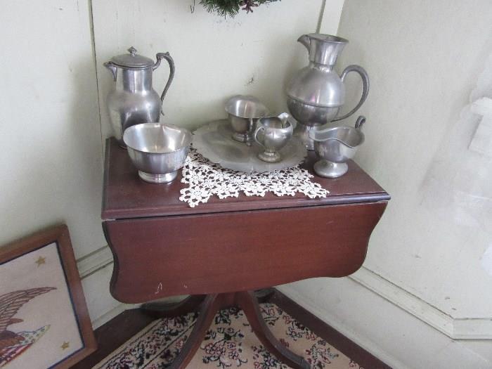 A small Duncan Phyfe drop leaf table with pewter pieces on top of a hand made lace doily.  This sale has about 30-50 hand made lace doilies. 