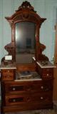 1880s Victorian drop front marble top walnut and burl paneled dresser on rollers with Renaissance style mirror with crested pedestal, boxes, and candle shelves. Glass pulls have been added