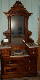 1880s Victorian drop front marble top walnut and burl paneled dresser on rollers with Renaissance style mirror with crested pedestal, boxes, and candle shelves. Glass pulls have been added
