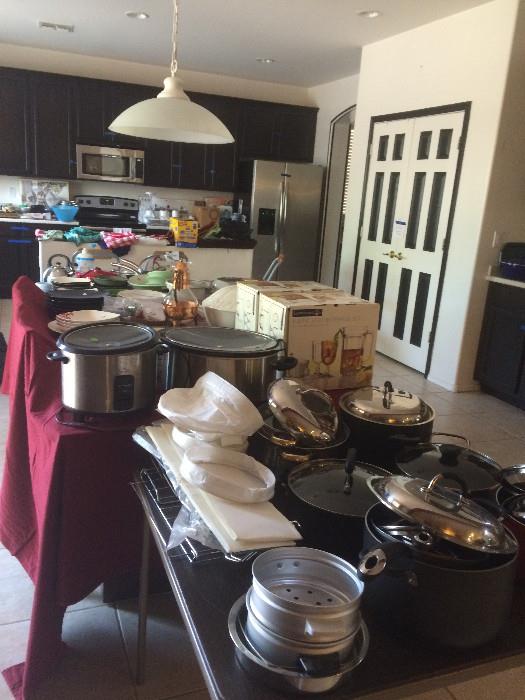 Kitchen full of pots, pans, dishes, glasses, crock pots and more.