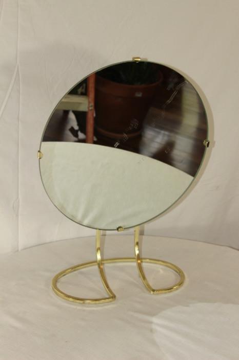Furnishing – Vanity mirror. Circular mirror is adjustable and on stand. One sided piece. Maker’s mark on back. Dated December 7, 1972