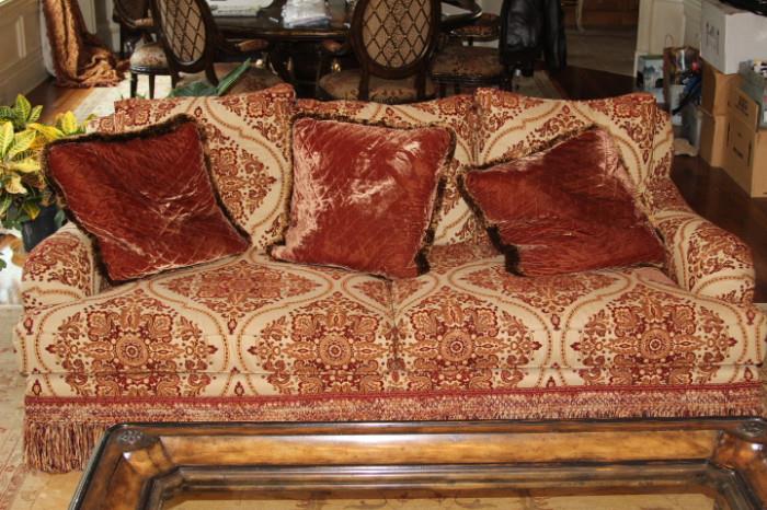 Furniture – Couch. Plush piece with throw pillows. Piece has fringed bottom. Upholstered piece with beige background and red symmetrical pattern. Piece marked Century Hickory Inc. Nice piece in good condition