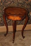 Furniture – Round side table. Piece has decorative legs and lip. Table top is round with different wood coloring making for a lovely piece. Metal trim around half the round table top.