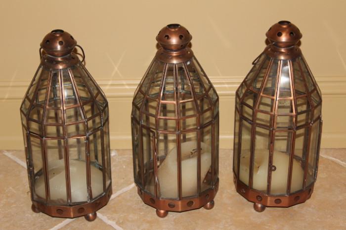 Furnishing – Group lot of three hanging candle lanterns. Pieces have burned and warped candle inside. One piece has cracks in the top glass parts.