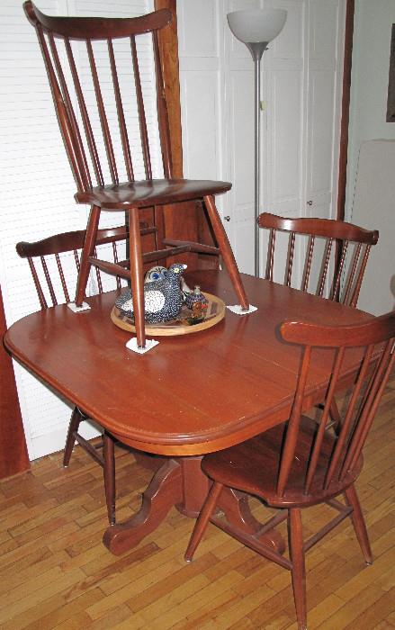 Cherry pedestal base table with four chairs and two leaves.