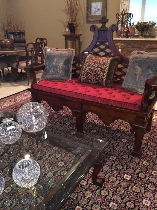 Ornate settee with red cushion; glass top coffee table