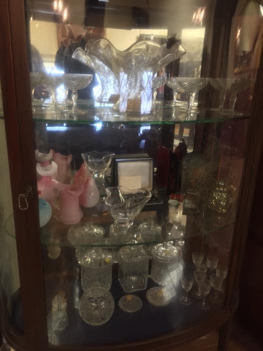 Bow front cabinet full of antique crystal glass, including Pairpoint