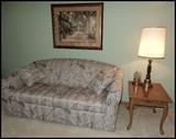 Hide-a-bed sofa and end table. Wall art.