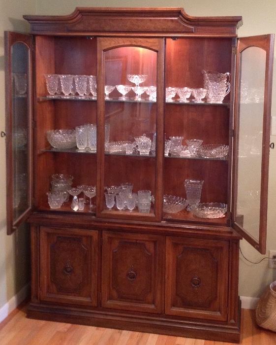 Beautiful three glass shelf hutch featuring Fostoria "Amerian" glassware.  Very nice and in mint condition. The hutch sits well in any room has three glass shelves plus three cabinet doors and has a light.  Very nice.