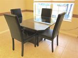 Glass top table with metal base and 4 faux leather chairs.