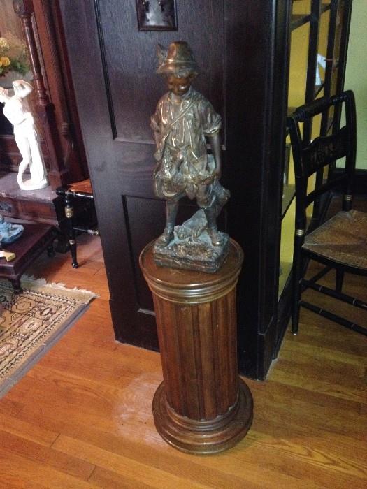 tall statue of little boy.  Wood pillar for displaying statues or plants.