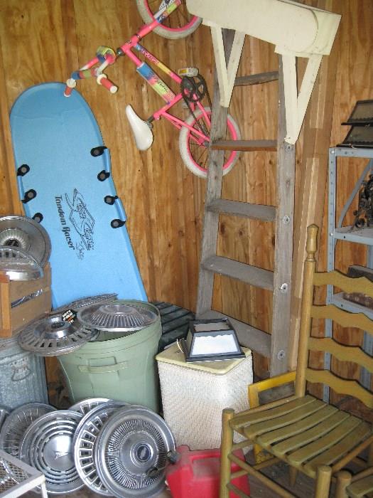 various hub caps, old ladder, ladder back chairs, small pink bike