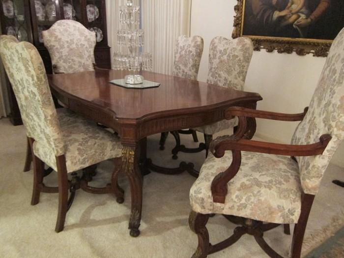 Late 19th to early 20th century Italian mahogany dining suite with parcel gilt carving. Includes table with two leaves, two armchairs, four side chairs and table pads. Chairs come with original pierced carved crest finials (not shown).