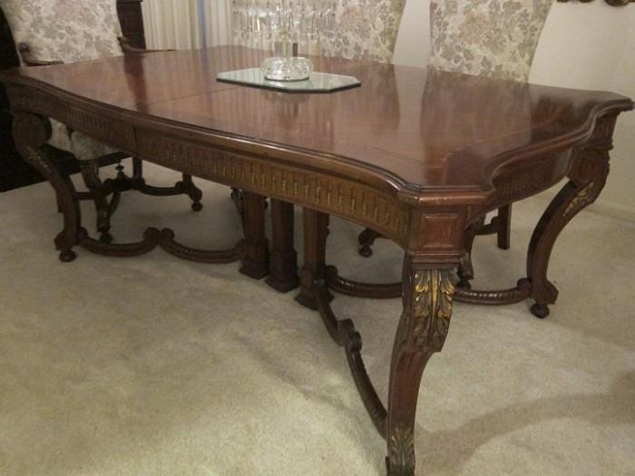 Late 19th to early 20th century Italian mahogany dining table with parcel gilt carving and inlaid banding. Comes with two leaves and table pads.
