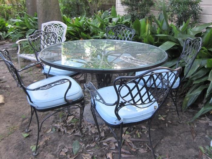 Set of five wrought iron chairs and matching glass top table.