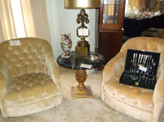 Pair of tufted swivel club chairs and black marble top table with pineapple base