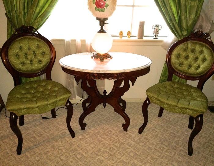 Rounding out the formal living area: two Victorian-style side chairs with carved-rose detail matching that of marble-top tables; notice antique lamp