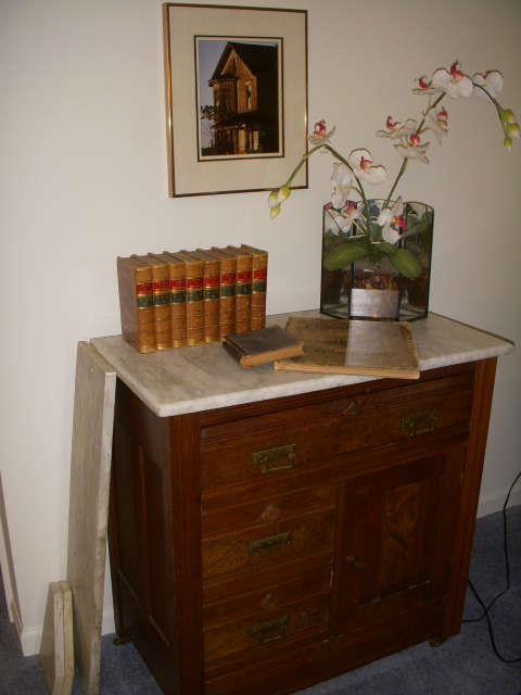 Marble top commode with antique books displayed.  Pieces of marble to side are the original back and side-splash pieces.