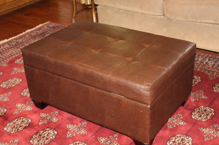 leather storage ottoman atop a very sharp looking rug!