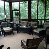 Two chairs with ottomans, sofa, coffee table porch furniture; antique rocker in foreground; custom made sisal rug